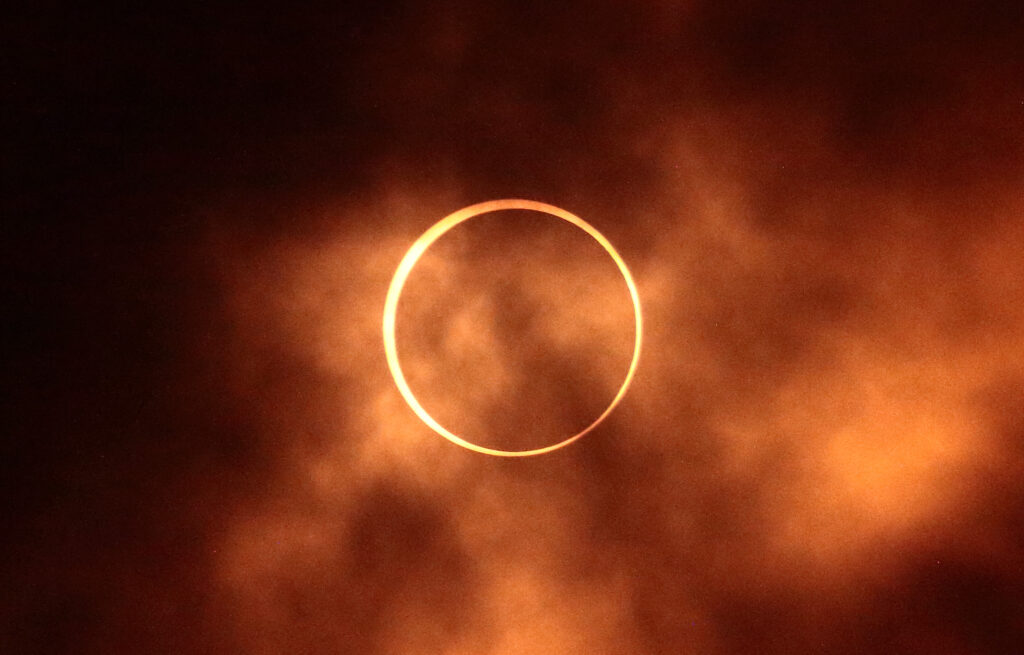 Annular Eclipse (Ring of Fire) with "fiery" clouds surrounding it.