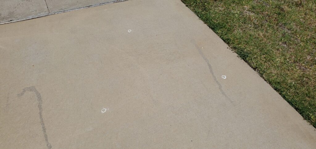 Three chalk circles on a paved driveway.
