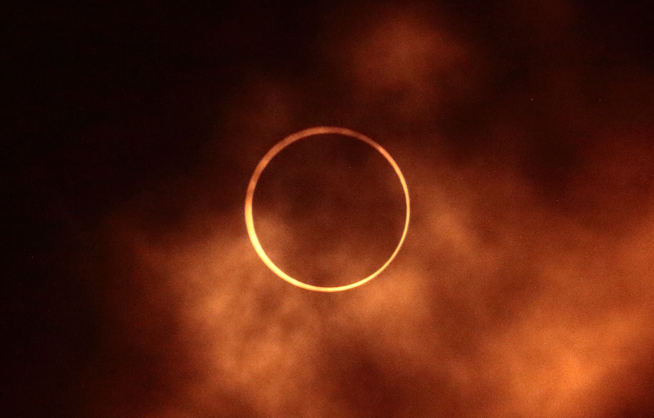 Annular Eclipse (Ring of Fire) with "fiery" clouds surrounding it.